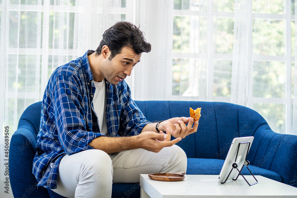 Caucasian man at home eating a slice of pizza food online together with her girlfriend in video conference with digital tablet for a online meeting in video call for social distancing