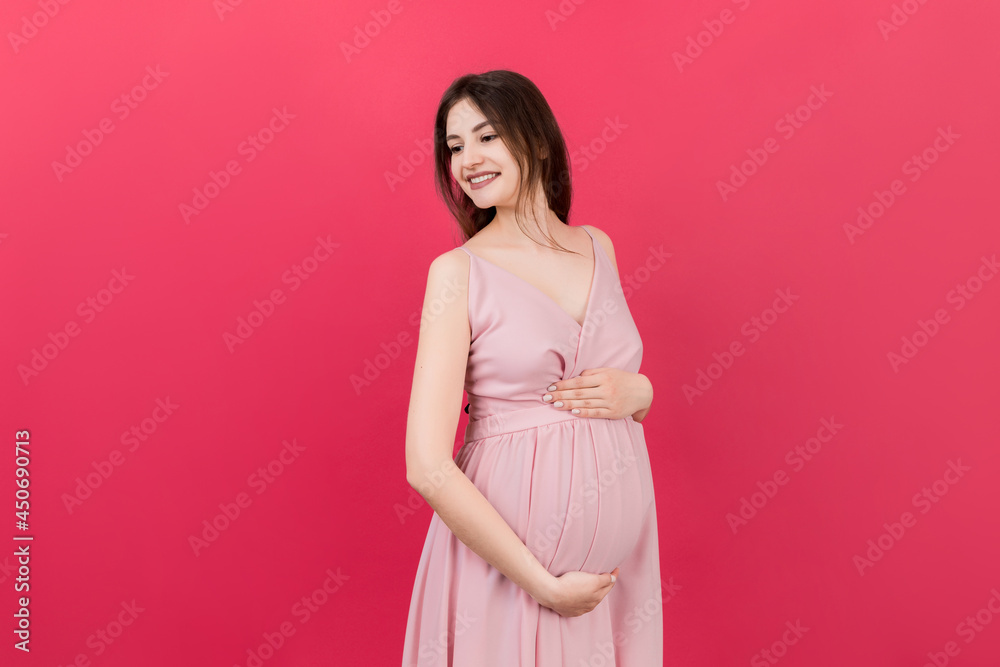 Happy pregnant woman touching her abdomen at Colored background. Future mother. Expecting of a baby. Copy space Happy pregnant woman touching her abdomen at Colored background. Future mother. Expecting of a baby. Copy space
