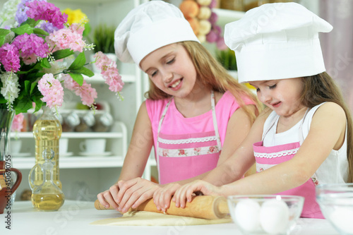 Cute little girls in hats making dough