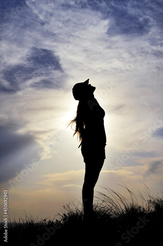 Silhouette of a woman in a full-length cap looking at the sky.