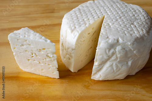 slice of fresh white mine cheese on the wooden board. photo