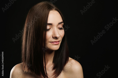 Portrait of pretty young woman with gorgeous chestnut hair on black background, space for text