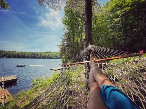 Female legs in the end of a hammock with a view of docks on a lake. photo