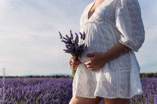 View of a pregnant woman's belly holding a bouquet of lavender flowers photo