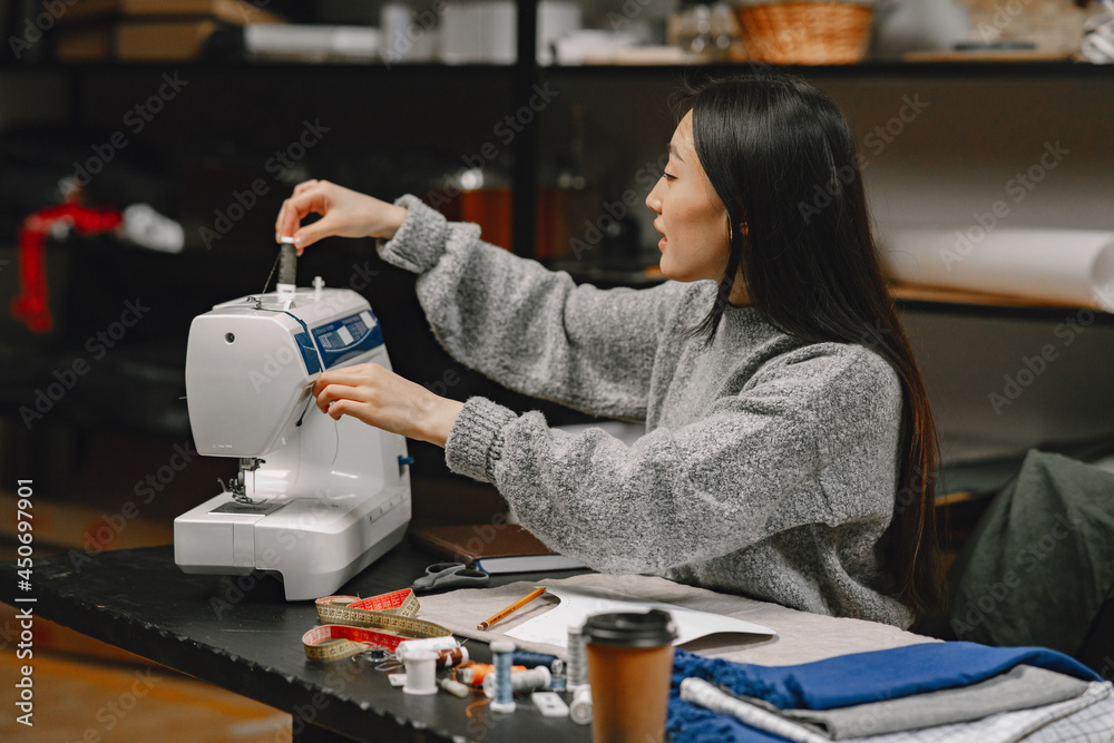 Professional young female tailor working in workshop Professional young female tailor working in workshop