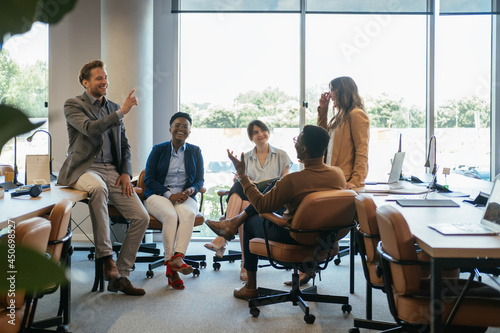 Group of Smiling Businesspeople in a Casual Meeting at their Company.

Team of five multi-ethnic employee having fun working together in an open plan office with big windows.