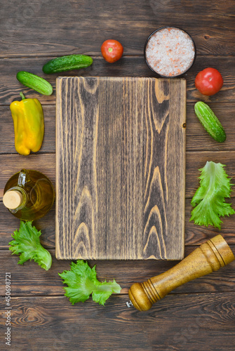 food and culinary background with copy space for text top view, pepper mill, pink himalayan salt and cooking ingredients, fresh vegetables tomatoes, cucumbers on the kitchen wooden table