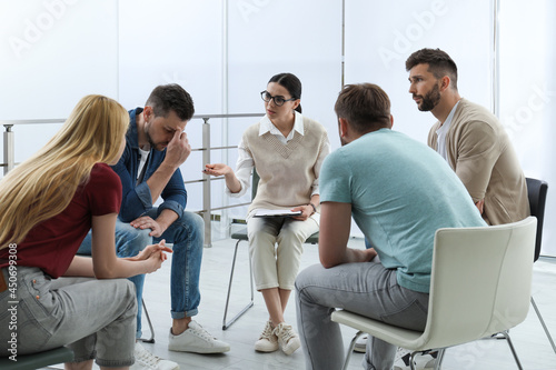 Psychotherapist working with group of drug addicted people at therapy session indoors © New Africa