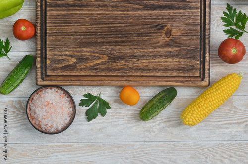 food and culinary background with copy space for text top view, pink himalayan salt and cooking ingredients, fresh vegetables tomatoes, cucumbers, corn  on the kitchen wooden table