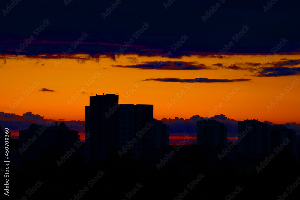 A picturesque sunset in the city with silhouettes of houses.