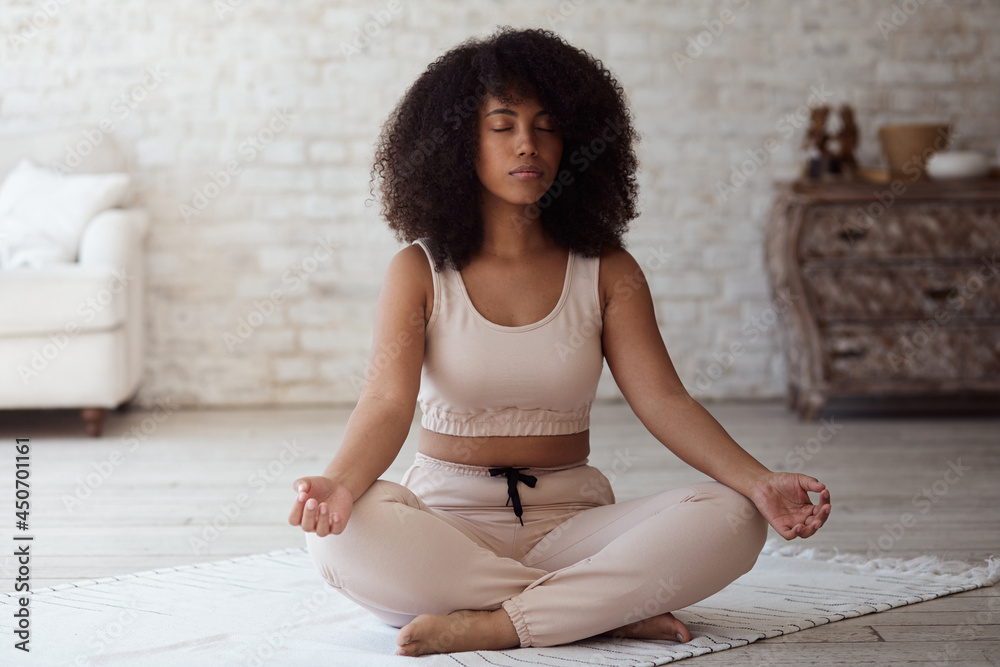 Yoga and breathing techniques practiced by a young, cheerful mixed-race woman. At home, a black woman practices calm relax harmony Zen mindfulness meditation. Self-isolation of Coronavirus Covid 19. Yoga and breathing techniques practiced by a young, cheerful mixed-race woman. At home, a black woman practices calm relax harmony Zen mindfulness meditation. Self-isolation of Coronavirus Covid 19.