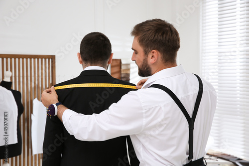 Obraz na plátně Professional tailor measuring client's shoulder width in atelier