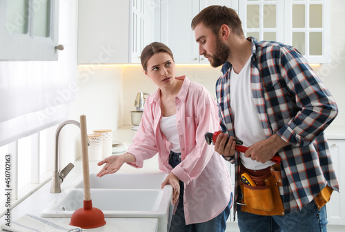 Εκτύπωση καμβά Young woman complaining to plumber about clogged sink in kitchen