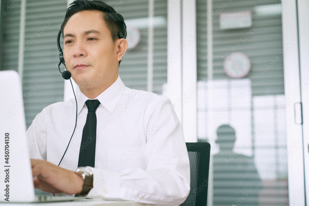 Asian business male call center working with headset and laptop for support customer problems Asian business male call center working with headset and laptop for support customer problems