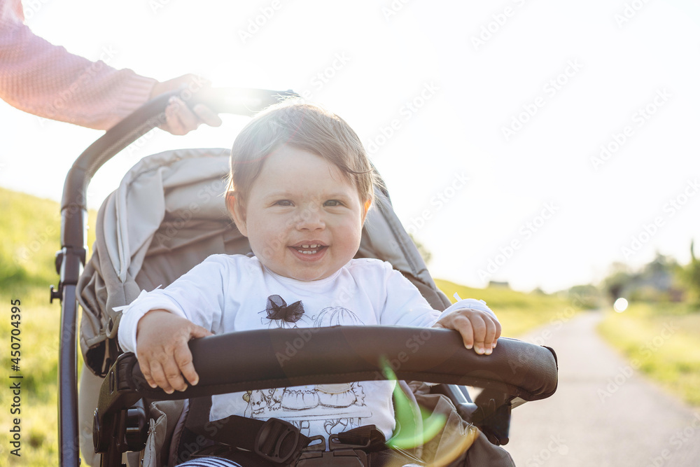 Happy laughing baby girl enjoying a walk in countryside sitting in the modern stroller - Sweet child in buggy showing first teeth in a big laugh - Traveling with young kids - Joyful childhood concept Happy laughing baby girl enjoying a walk in countryside sitting in the modern stroller - Sweet child in buggy showing first teeth in a big laugh - Traveling with young kids - Joyful childhood concept