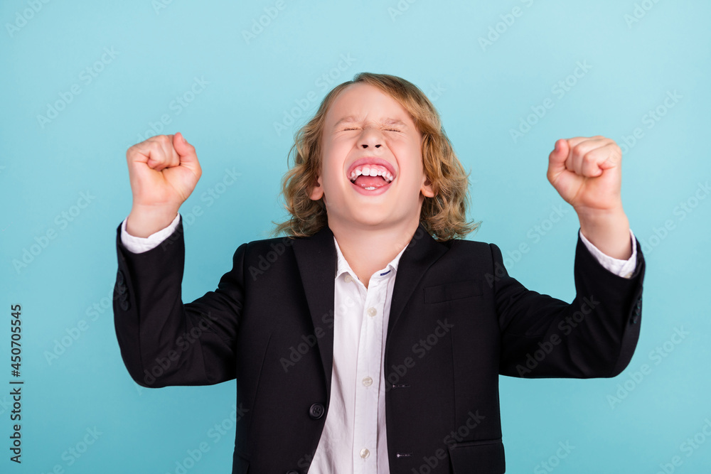 Photo of cool little blond boy yell hands fists wear uniform isolated on blue color background Photo of cool little blond boy yell hands fists wear uniform isolated on blue color background