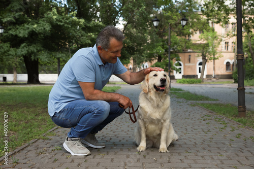 Happy senior man with his Golden Retriever dog in park