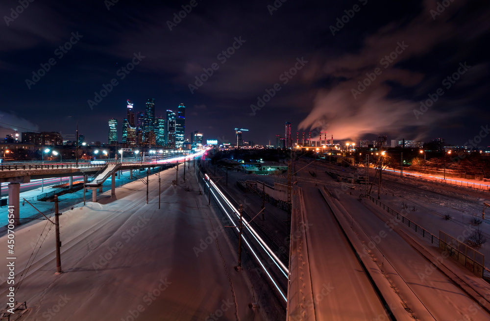 A view of railways and roads against Moscow cityscape with Moscow-City at winter night