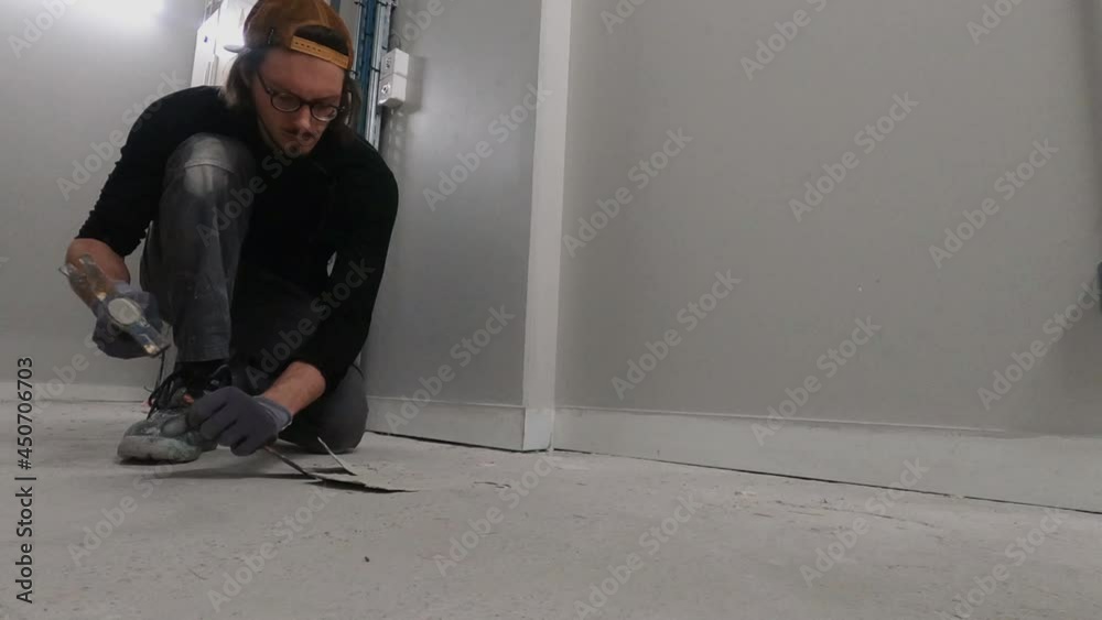 Worker uses a hammer and a chisel to remove the paint residue Worker uses a hammer and a chisel to remove the paint residue
