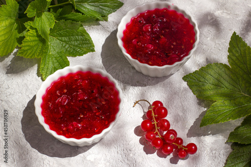 Two dishes with healthy red currant jam on a light table photo