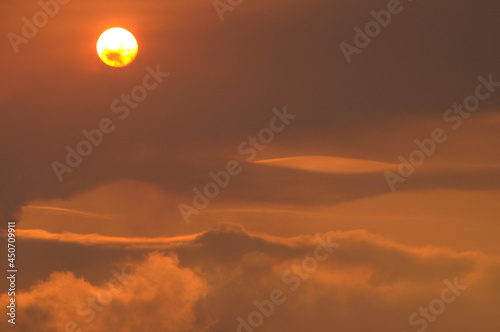 Red sun on fire. Cloudy sunset landscape high in the clouds. Late autumn red sky. Natural landscape calm scene red sun and red sky. A mesmerizing picture high in the sky.