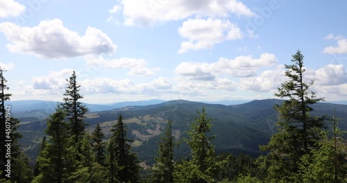 Motion Timelapse Of Fluffy Clouds Moving In The Sky Over Lush Green Coniferous Trees And Mountains. View From Hasmasul Mare In Romania. wide shot photo