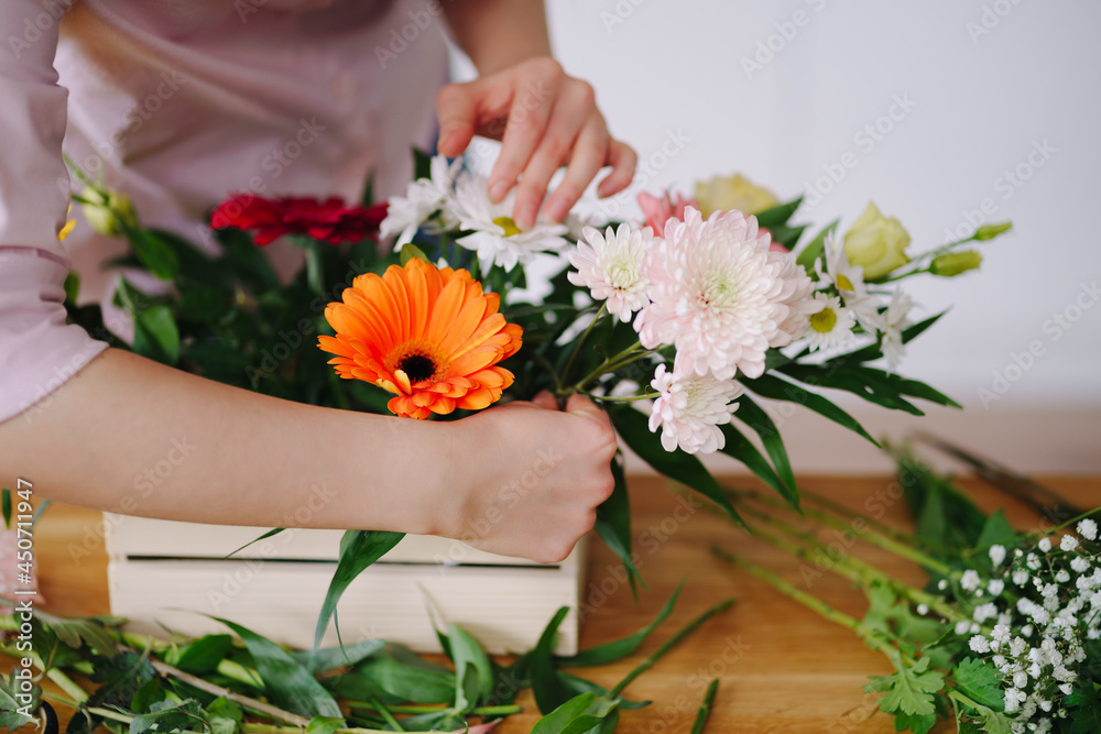 Florist at work: young brunette woman hands making fashion modern composition of different flowers at home