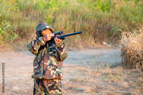 young hunter in a protective suit with a rifle getting ready to hit the target