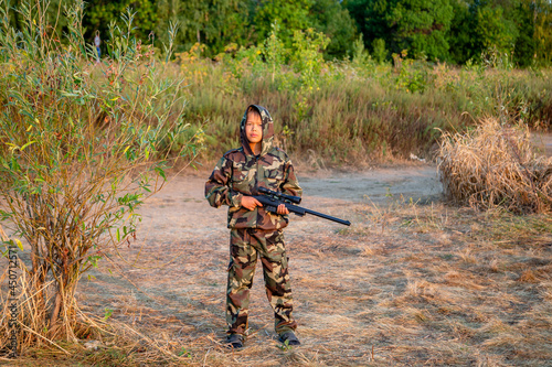 young hunter in a protective suit with a rifle getting ready to hit the target