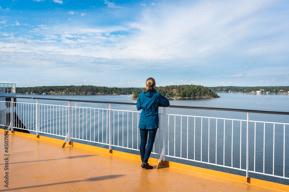 Woman female on upper deck of cruise travel. Panoramic view from large beautiful modern cruise ship. Girl viewing sea from observation deck. Green forest coastline. Water trip adventure lifestyle.