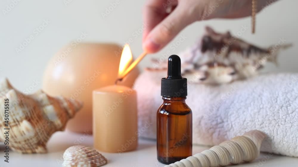Brown glass bottles with serum, essential oil or other cosmetic product. A woman's hand lights candles. Natural organic cosmetic packaging, skin care and spa concept. Brown glass bottles with serum, essential oil or other cosmetic product. A woman's hand lights candles. Natural organic cosmetic packaging, skin care and spa concept.