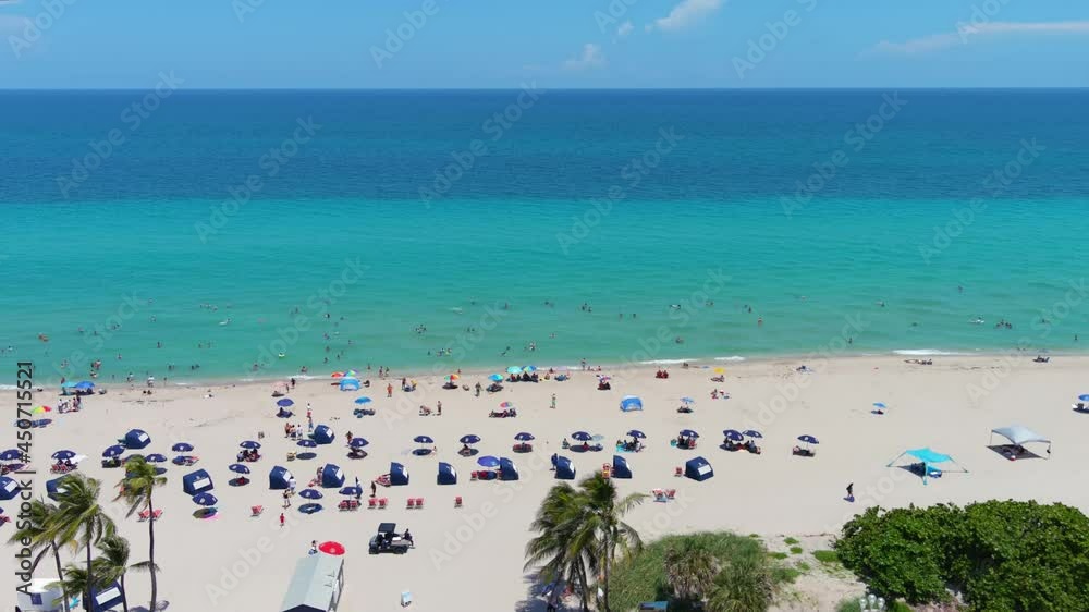 Aerial Hollywood Florida fly south along beach coastline and ocean view on sunny days with umbrellas Aerial Hollywood Florida fly south along beach coastline and ocean view on sunny days with umbrellas