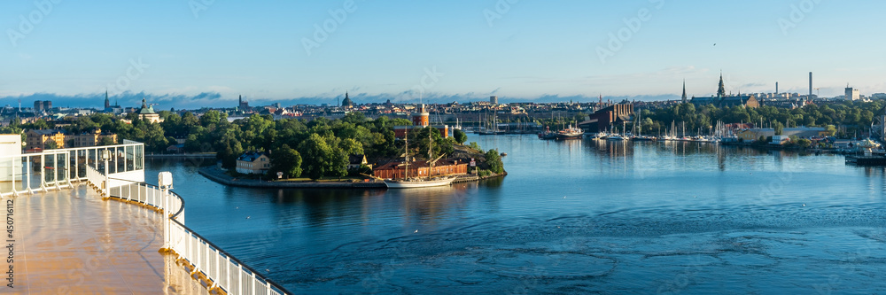 Naklejka premium Panoramic beautiful View of Stockholm Swedish capital from big modern cruise ship. Ship passes through the islands of archipelago. Towers of the buildings and city dominants are visible. Water trip.