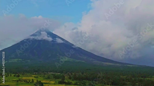 Aerial view - camera flying over rice fields with Mayon Volcano in the background - bright and sunny day. photo