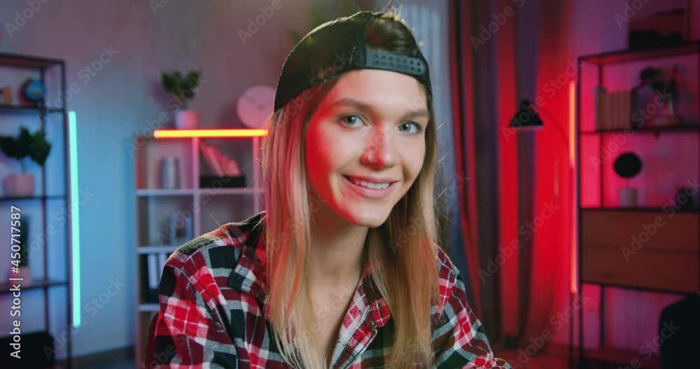 Camera shooting on cute happy smiling blond female freelancer with earring in nose which working on laptop at home in the evening and looking into camera with satisfied face expression Camera shooting on cute happy smiling blond female freelancer with earring in nose which working on laptop at home in the evening and looking into camera with satisfied face expression