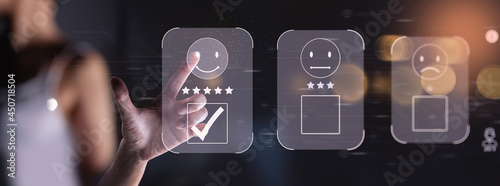 Customer service and Satisfaction concept ,Businesswoman touching the virtual screen of modern computer on the happy Smiley face icon to give satisfaction in service. 5-star rating very impressed