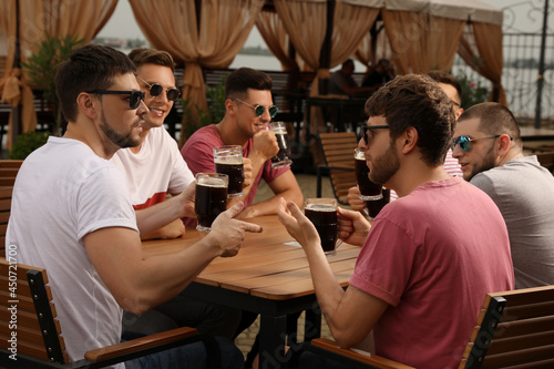 Friends with glasses of beer in outdoor cafe