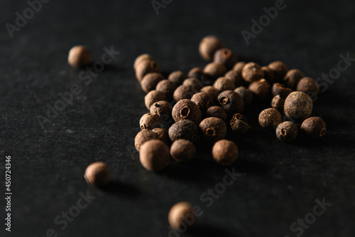 Fotografia allspice black peppercorns, seasoning for food, sprinkled on gray background