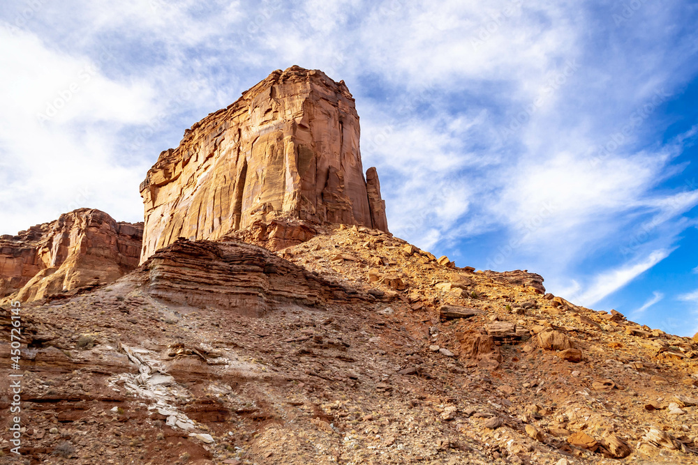 Fototapeta premium Looking up at a butte with wispy white clouds and a brilliant blue sky in Canyonlands National Park.
