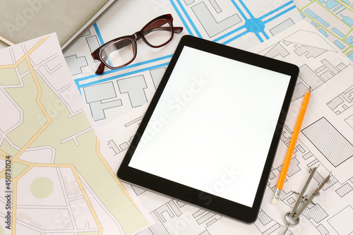 Office stationery, eyeglasses and tablet on cadastral maps of territory with buildings