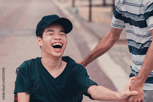 фотографія Asian disabled teenager boy on wheelchair and carer in public places, Lifestyle of happy disability child travel holidays at the road in front of beach