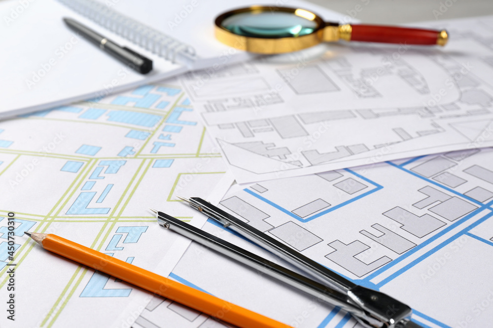 Office stationery and cadastral maps of territory with buildings on table Office stationery and cadastral maps of territory with buildings on table