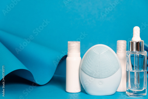 Art colourful geometry blue style and skin care cosmetics. Origami in a blue colour and cosmetics in white and blue colours: serum, face cream, face tonic. Paper mock up and luxury cosmetic. 