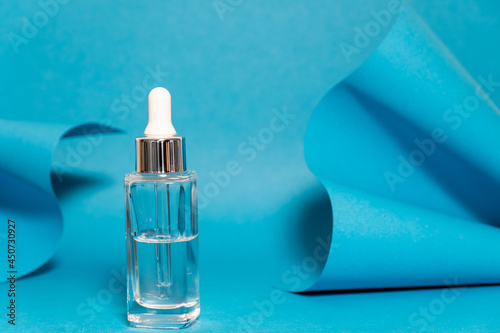 Art colourful geometry blue style and skin care cosmetics. Origami in a blue colour and cosmetics in white and blue colours: serum, face cream, face tonic. Paper mock up and luxury cosmetic. 