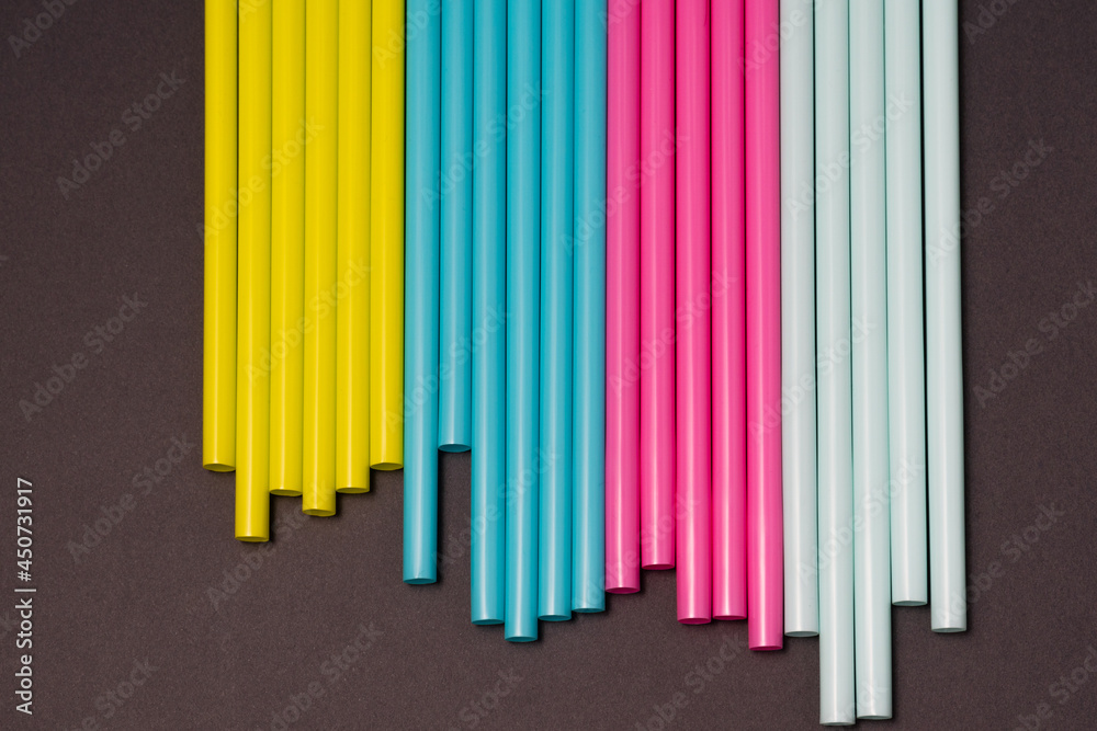 Fototapeta premium colourful cocktails straw for drinks in pink, yellow, blue colours on a dark background 