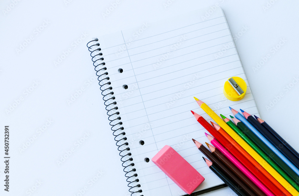 notebook in line with colored pencils with an eraser. sharpener on a white background