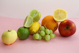 fresh fruit apple, lime, avocado, lemon, orange, grapes on a light pink background