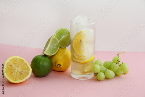 cocktail with lemon, lime and min. lime and lemon on a pink background.lime slices and lemon in the cut