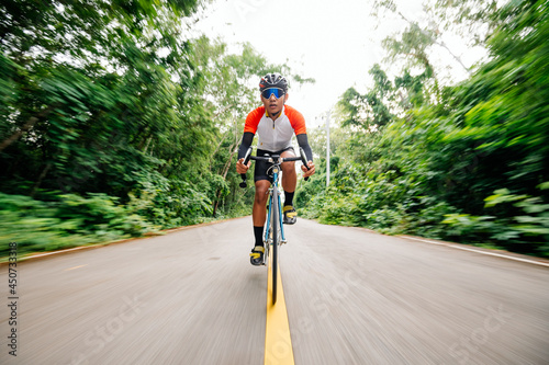 Fototapeta Naklejka Na Ścianę i Meble -  A man ride on bike on the road. Man riding vintage sports bike for evening exercise. A man ride bicycle to breathe in the fresh air in midst of nature, meadow, forest, with evening sun shining through