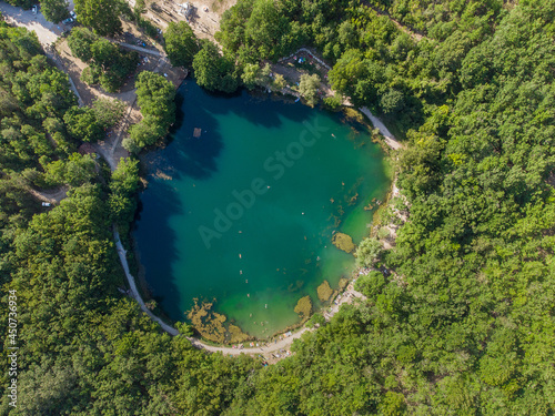 Round small lake with clear water sorrounded by trees , overhead view